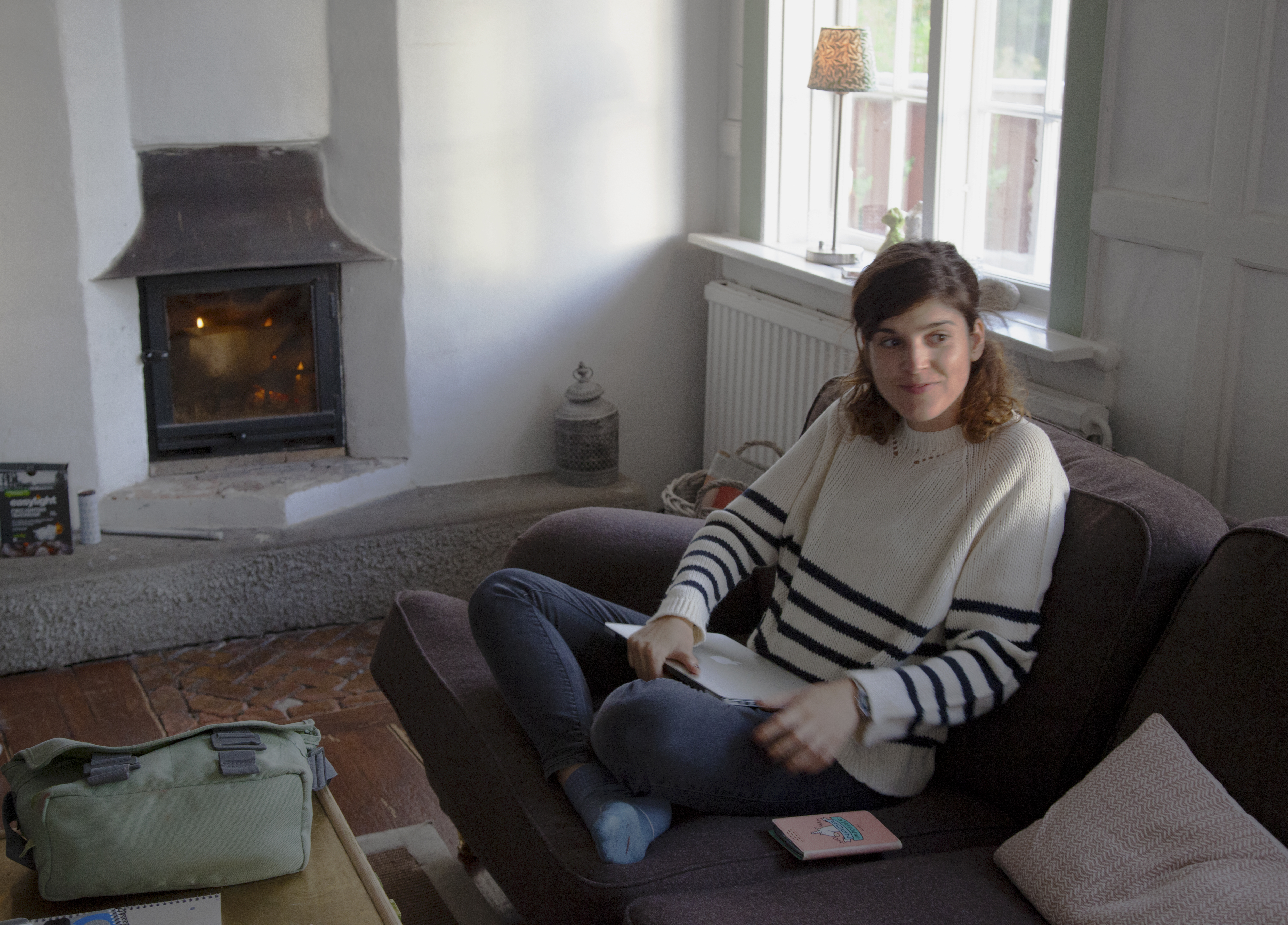 Image 16. Berta is seating in the living room. A fireplace is burning in the background.